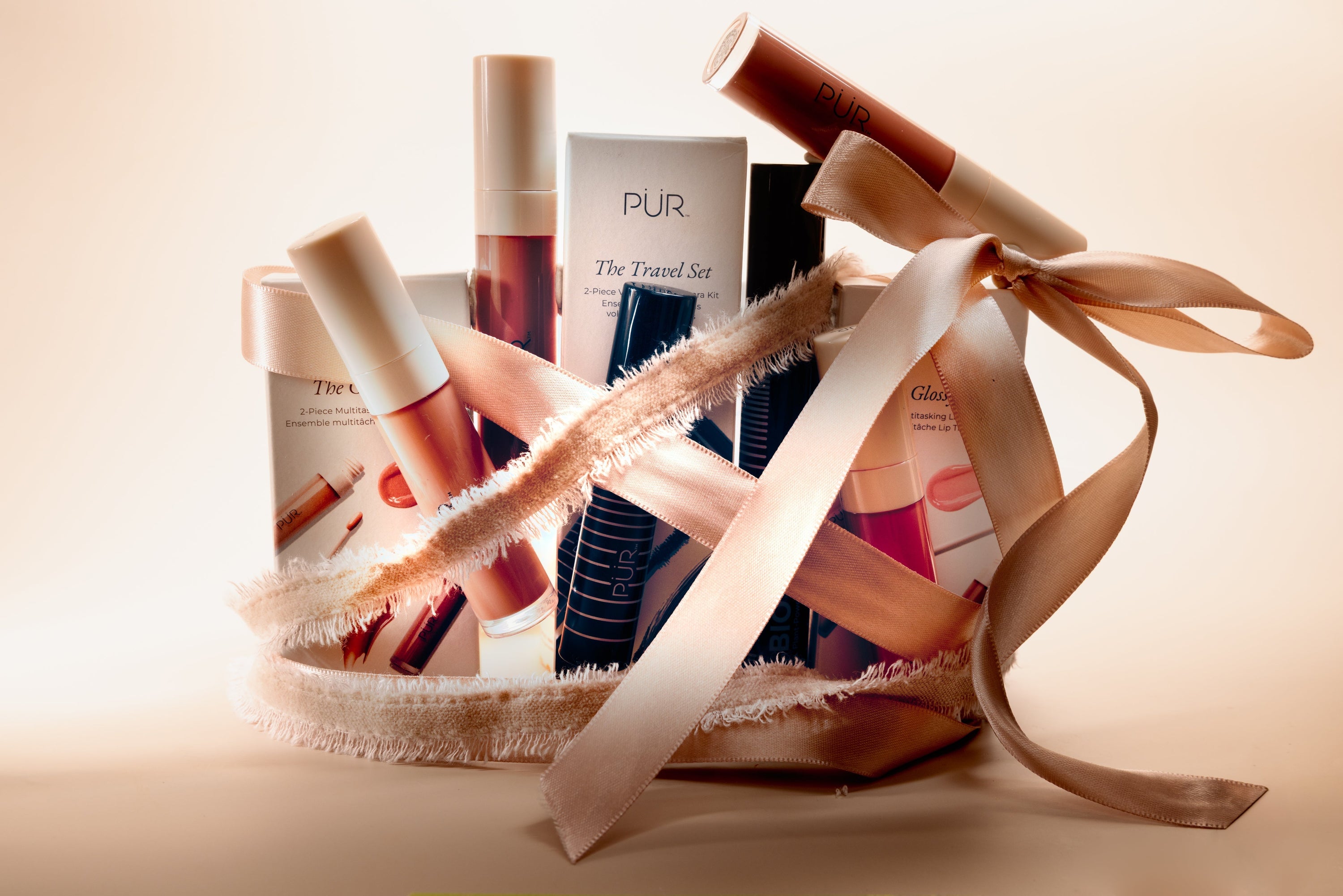 PUR beauty gift set with tubes and boxes wrapped in a pale pink ribbon.