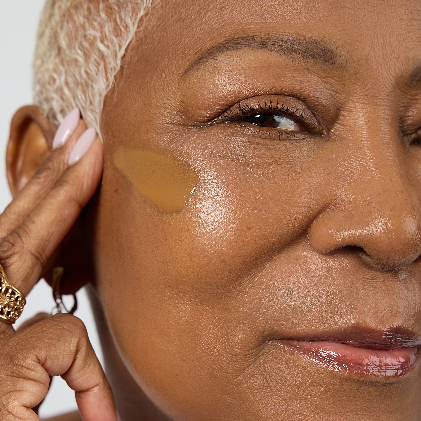 Close-up of a woman applying a beige concealer stick to her face Shade DG6 