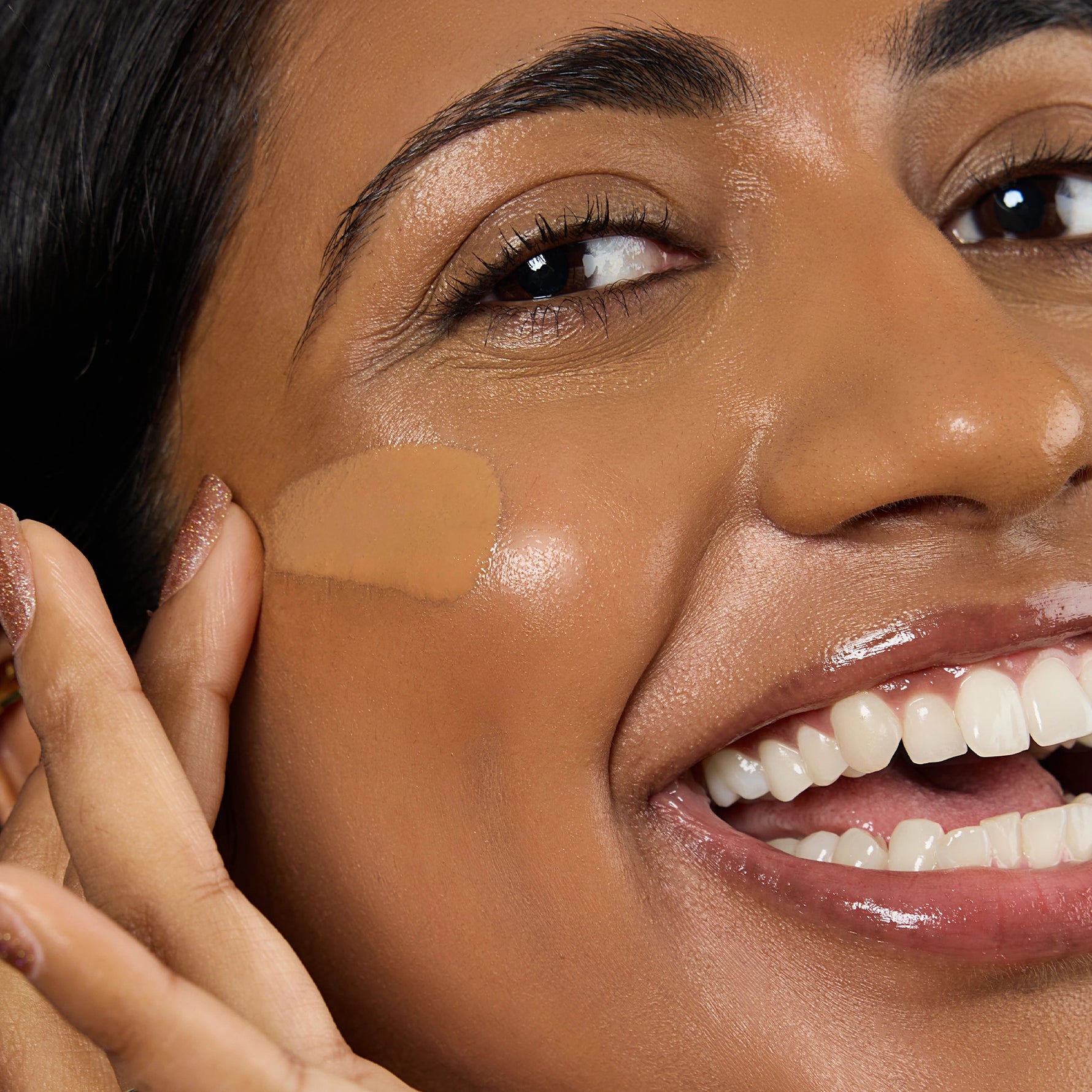 Close-up of a woman applying a beige concealer stick to her face Shade DP3 