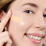 Close-up of a woman applying a beige concealer stick to her face Shade LN2  