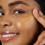 Close-up of a woman applying a beige concealer stick to her face Shade TN7 