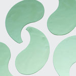Multiple green hydrogel eye patches laid flat on a light background to show shape and texture